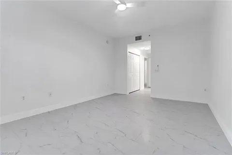 an empty room with a ceiling fan and window