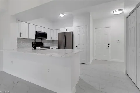 a kitchen with stainless steel appliances a refrigerator a microwave a sink and a refrigerator