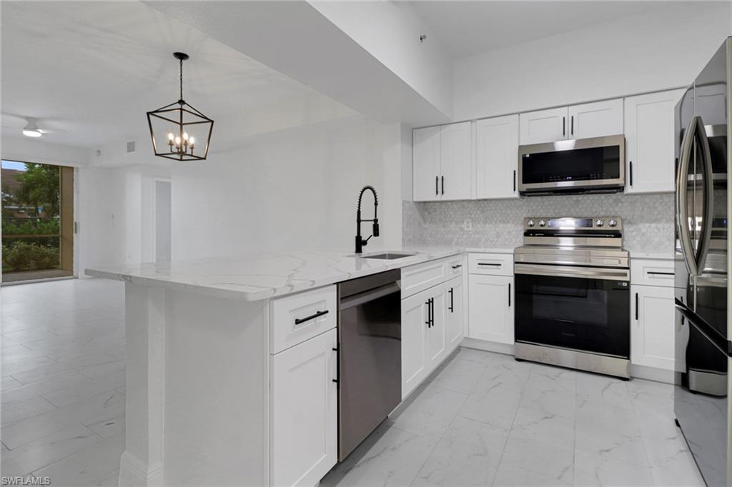 20170 Estero Gardens Circle, Unit 107 Estero, FL 33928 - Photo 5 of 44 a kitchen with stainless steel appliances a stove a microwave and a sink