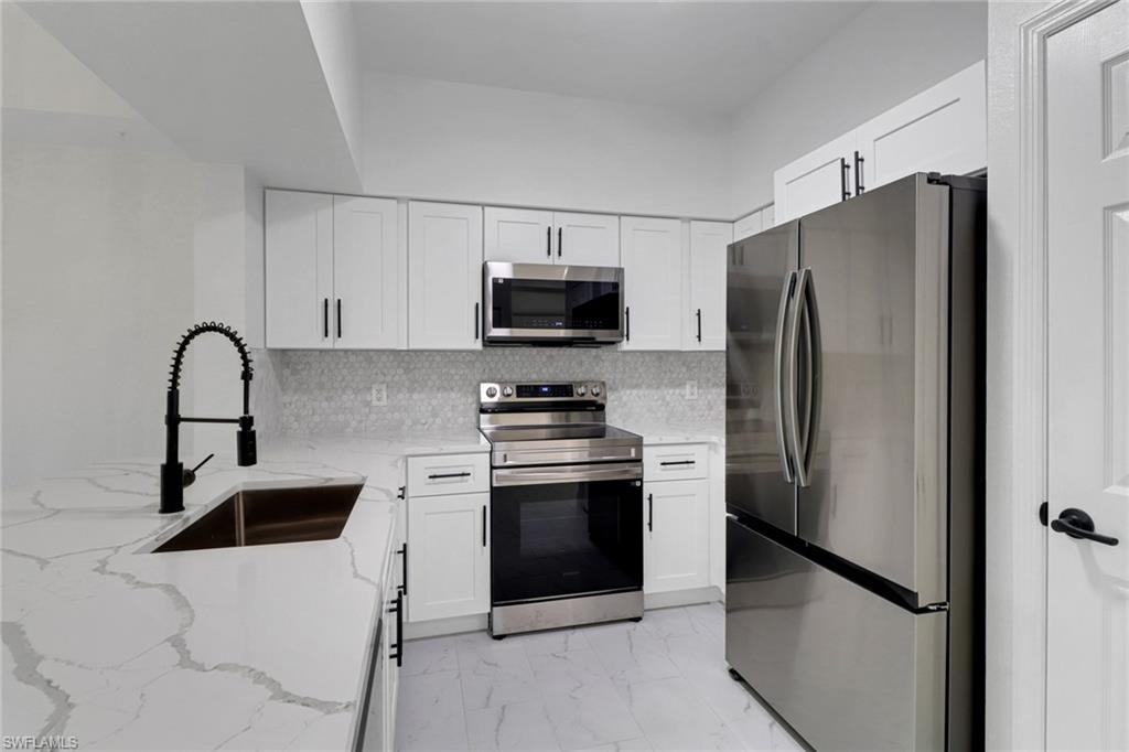 20170 Estero Gardens Circle, Unit 107 Estero, FL 33928 - Photo 6 of 44 a kitchen with stainless steel appliances a refrigerator stove and microwave