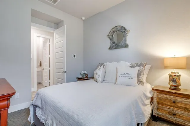 a bedroom with a bed and a lamp on dresser