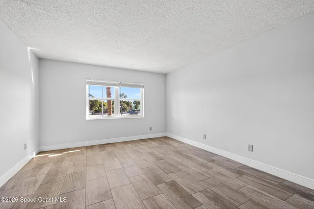 an empty room with wooden floor and window