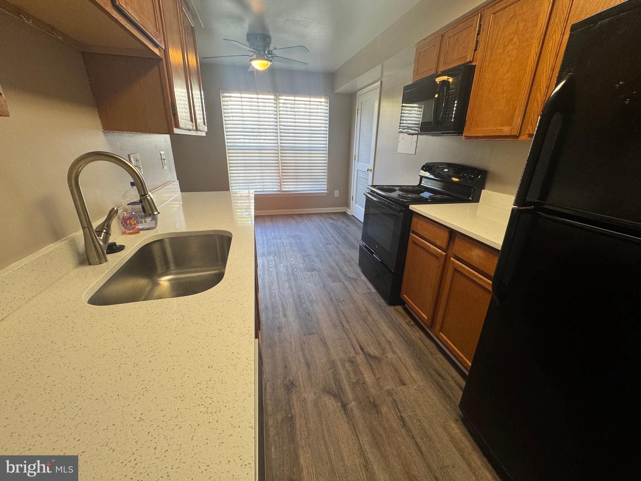 11263 Raging Brook Drive, Unit 253 Bowie, MD 20720 - Photo 11 of 22 a kitchen with wooden floor sink and stove