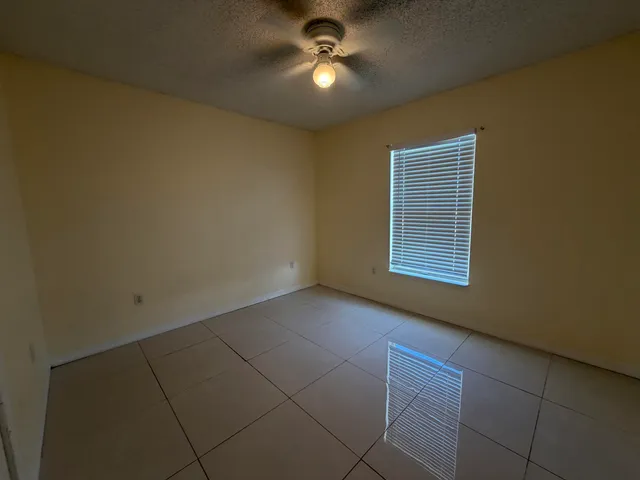 a view of empty room with ceiling fan and window