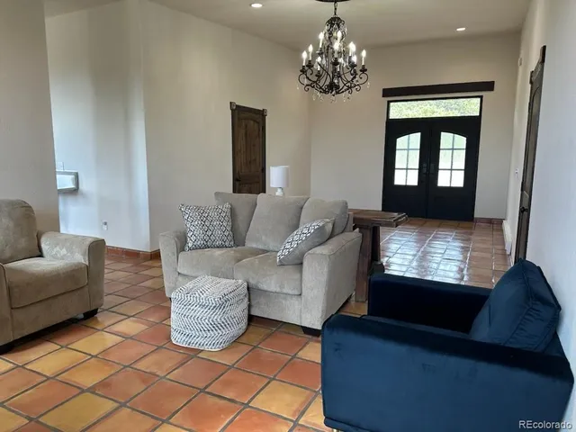 a living room with furniture a chandelier and a flat screen tv