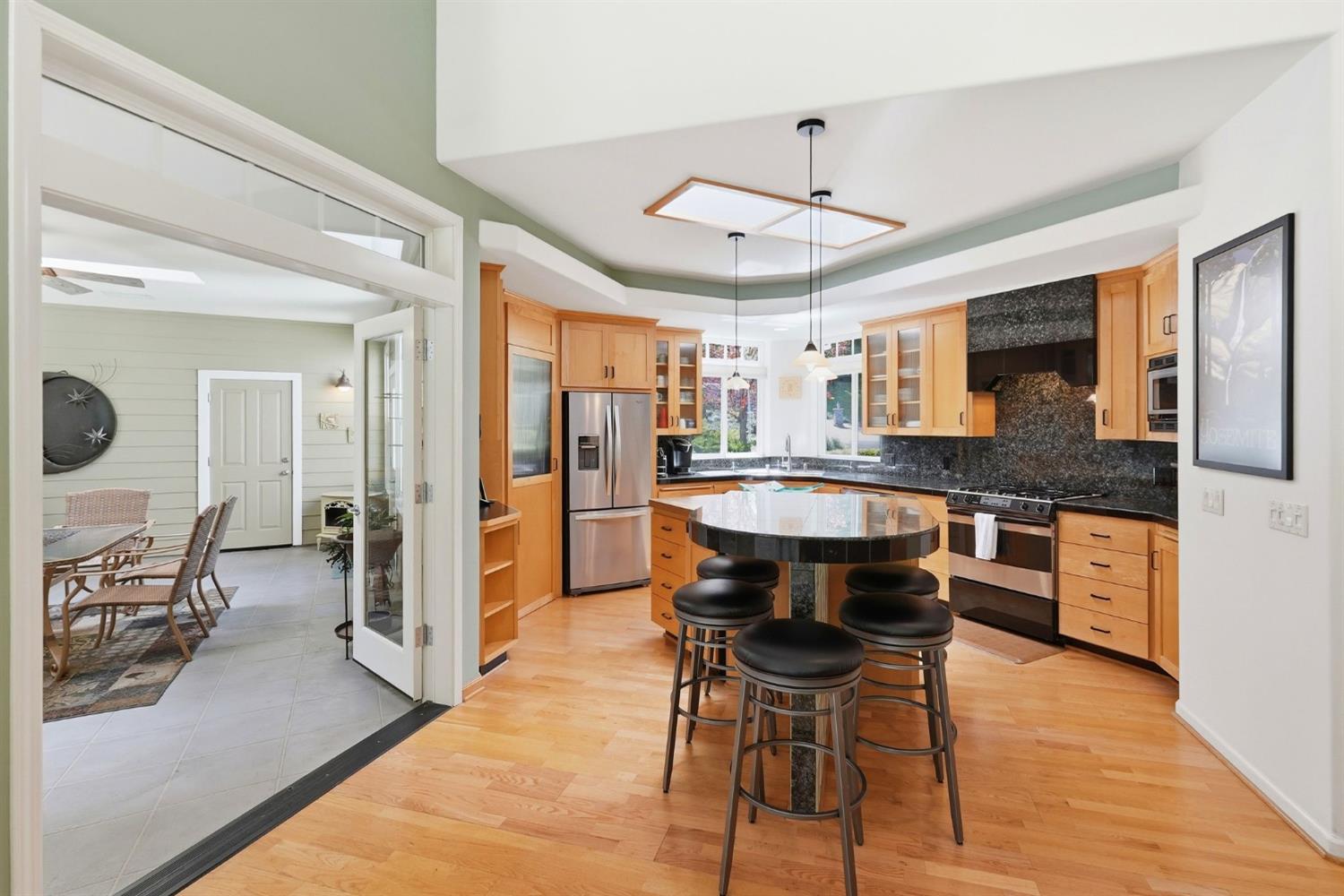10711 Murchie Mine Road Nevada City, CA 95959 - Photo 25 of 71 a kitchen with stainless steel appliances kitchen island granite countertop a stove a refrigerator a sink a dining table and chairs with wooden floor