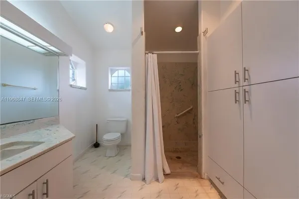 a bathroom with a granite countertop sink toilet and shower