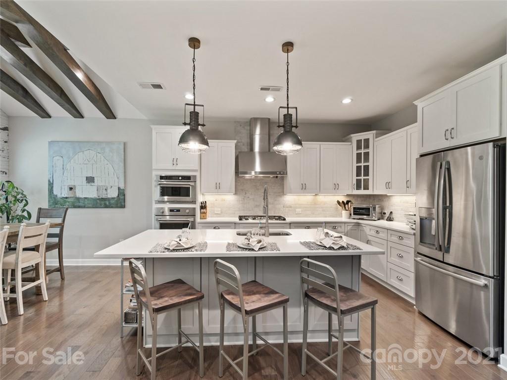 2822 Walker Road Matthews, NC 28105 - Photo 7 of 47 a kitchen with stainless steel appliances kitchen island granite countertop a dining table chairs and white cabinets