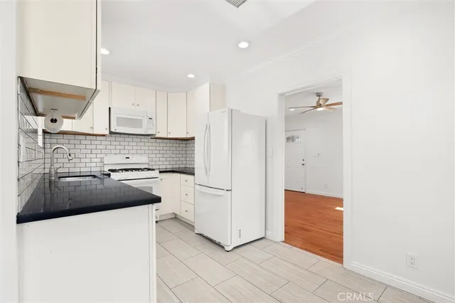 a kitchen with granite countertop white cabinets and stainless steel appliances