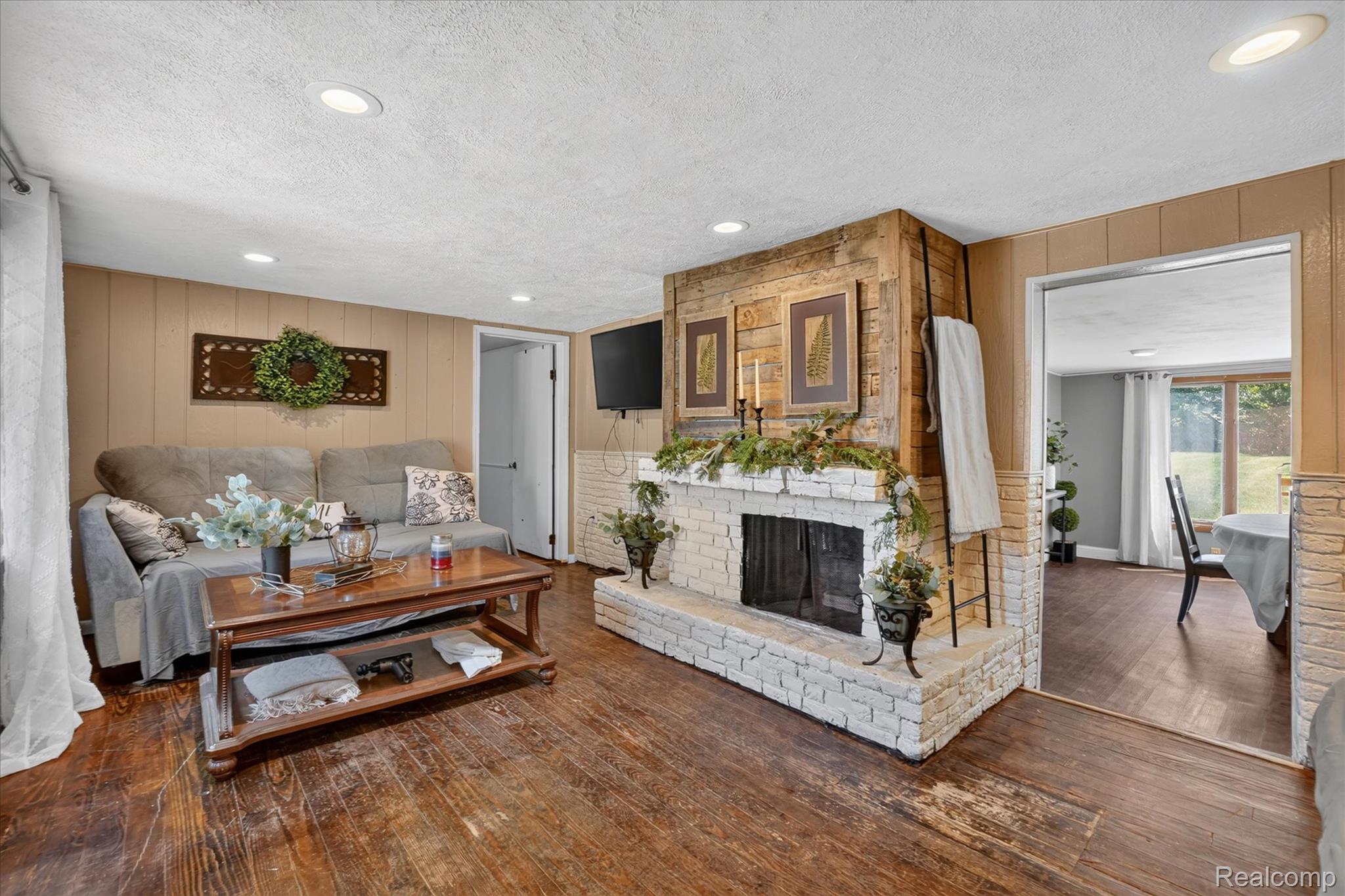 508 Deland Road Flushing, MI 48433 - Photo 8 of 38 Living area featuring a white brick fireplace with a wood mantle, wood-finish flooring, recessed lighting, and paneling