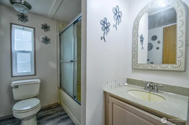 a bathroom with a granite countertop toilet sink and mirror