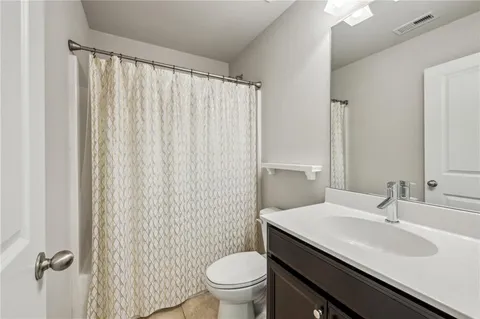 a bathroom with a granite countertop sink toilet and a mirror