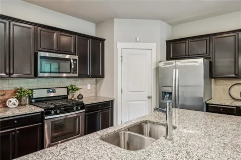 a kitchen with granite countertop a refrigerator stove and microwave