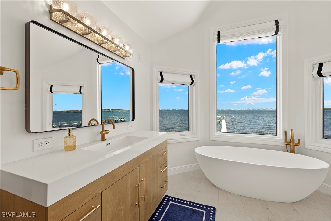 8451 Casa Del Rio Lane Fort Myers, FL 33919 - Photo 26 of 50 a bathroom with a double vanity sink a mirror and a bathtub