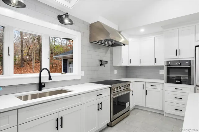 a kitchen with granite countertop a sink stainless steel appliances and white cabinets