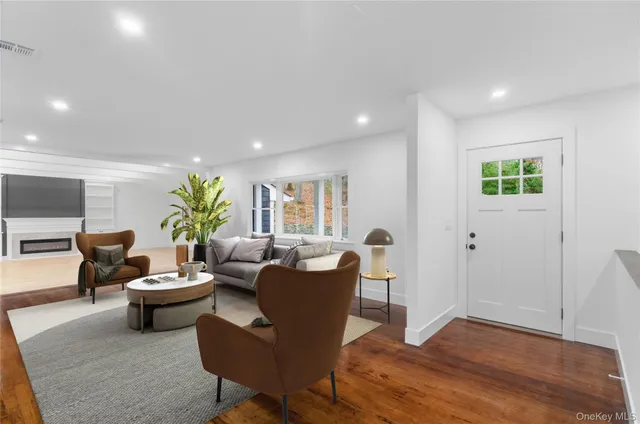 a living room with furniture a potted plant and open kitchen view