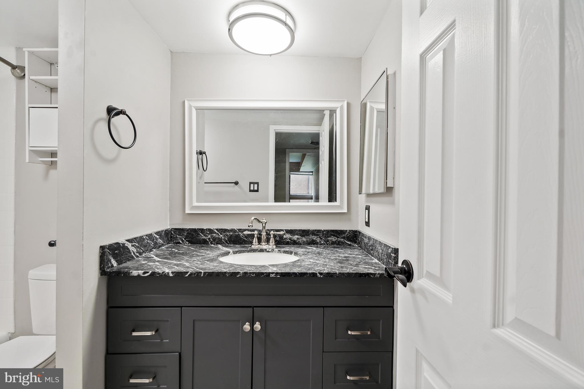 8487 Greenbelt Road Greenbelt, MD 20770 - Photo 16 of 29 a bathroom with a granite countertop sink and a mirror