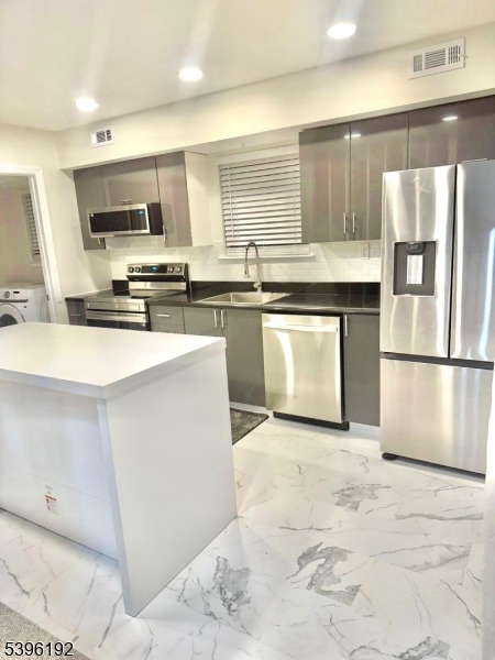 a kitchen with stainless steel appliances granite countertop a stove a sink and a microwave