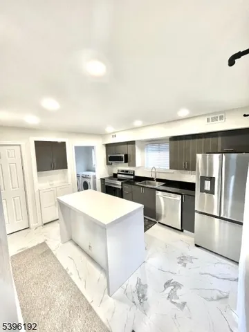 a large kitchen with kitchen island a stove a sink dishwasher and a refrigerator with wooden floor