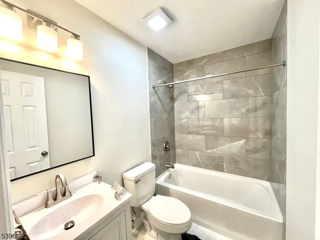 a bathroom with a bathtub shower sink vanity mirror and toilet