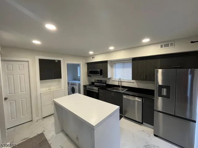 a large kitchen with a large counter top stainless steel appliances and cabinets