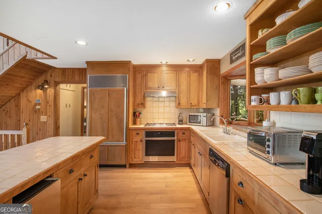 a large kitchen with stainless steel appliances granite countertop a sink and cabinets