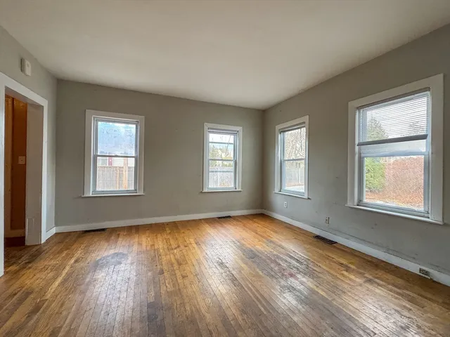a view of an empty room with wooden floor and a window