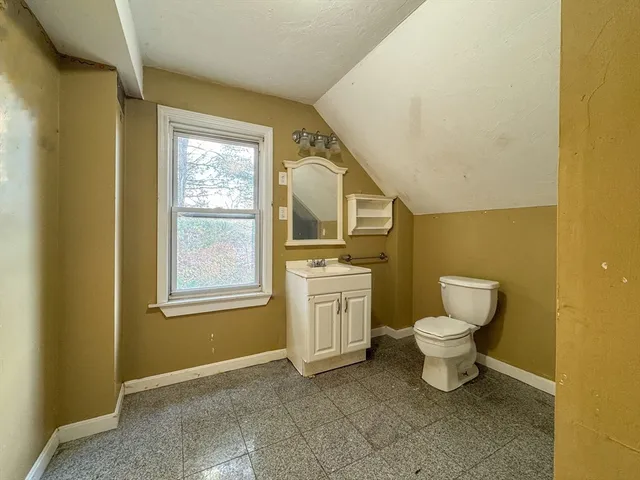 a bathroom with a toilet sink a window and mirror