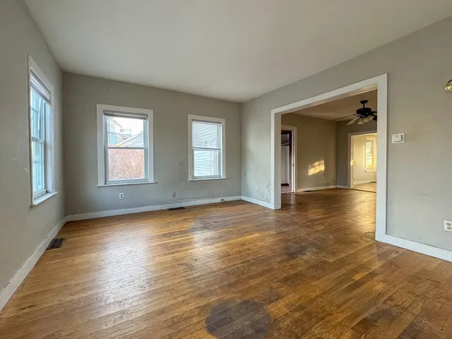 a view of empty room with window and wooden floor