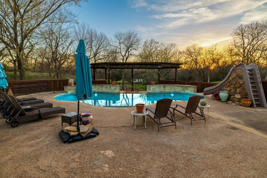 689 Jim Cannon Road Van Alstyne, TX 75495 - Photo 2 of 35 Pool at dusk featuring a patio area, a water slide, and a fenced backyard
