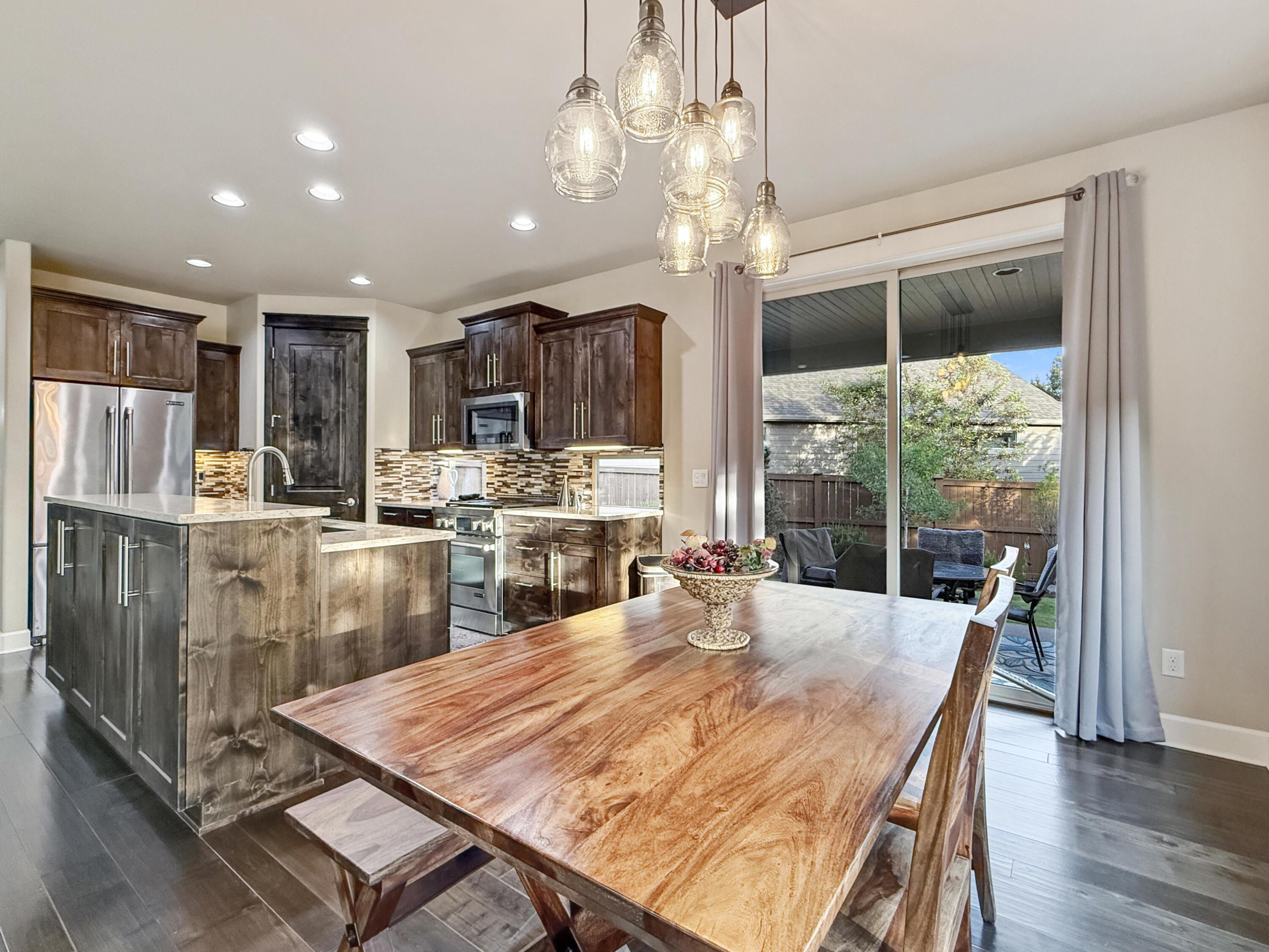 61072 Manhae Loop Bend, OR 97702 - Photo 10 of 63 a kitchen with stainless steel appliances kitchen island granite countertop a refrigerator a stove top oven and a dining table with wooden floor
