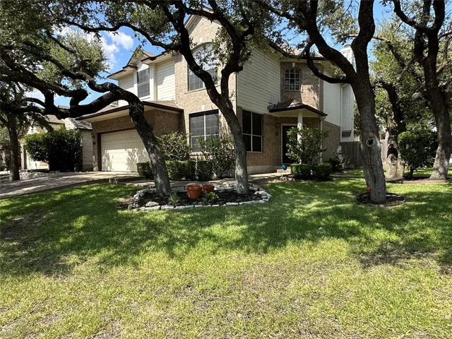 a view of house in front of a big yard with large trees