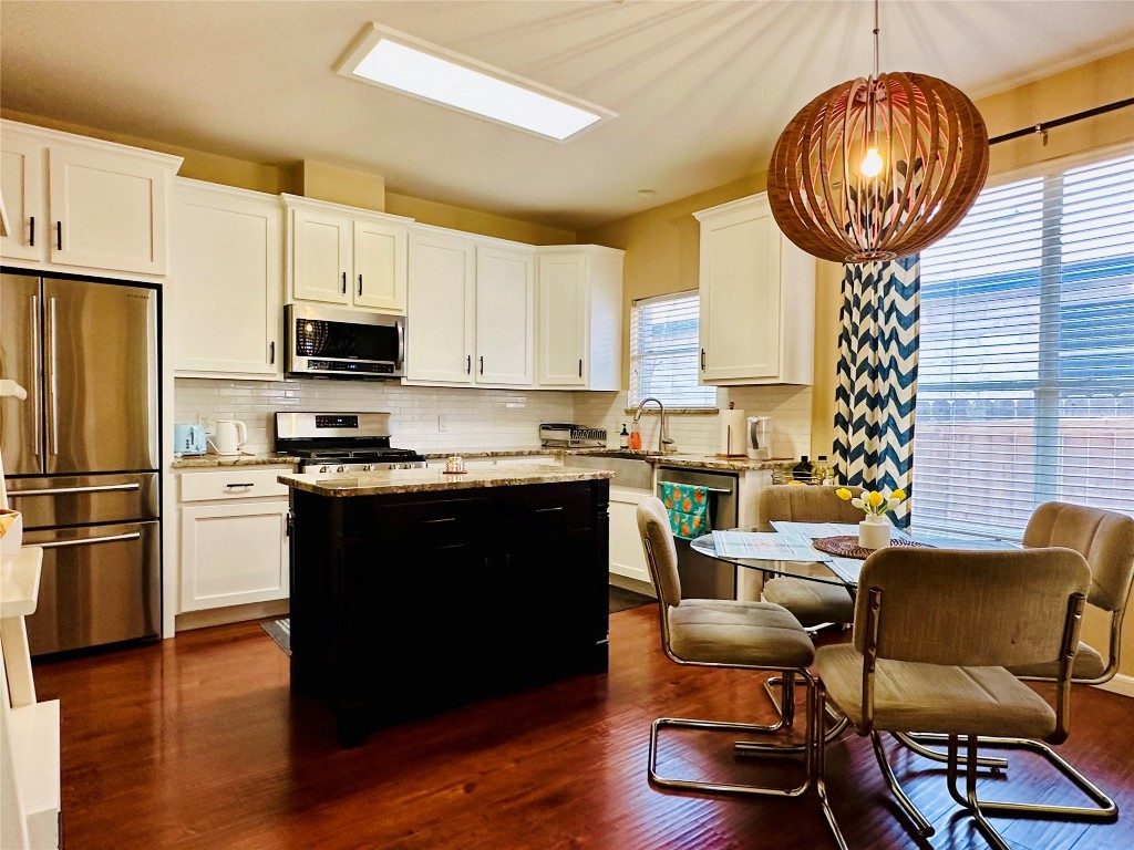 8300 Alvin High Lane Austin, TX 78729 - Photo 4 of 21 a kitchen with stainless steel appliances granite countertop a stove a refrigerator a microwave a dining table and chairs with wooden floor