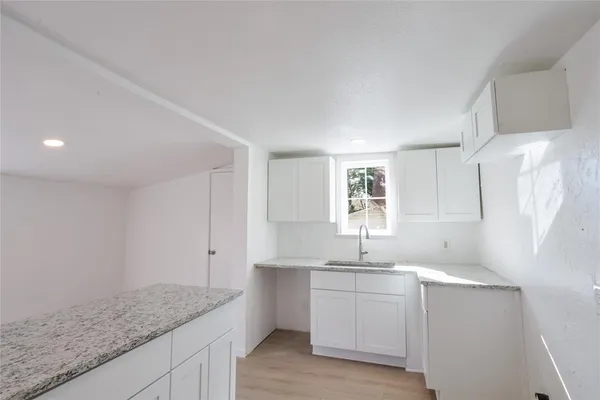 a kitchen with a sink dishwasher a stove and white cabinets with wooden floor