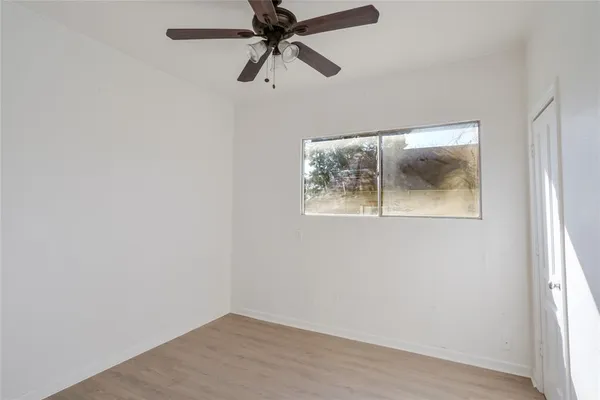an empty room with a window and a ceiling fan