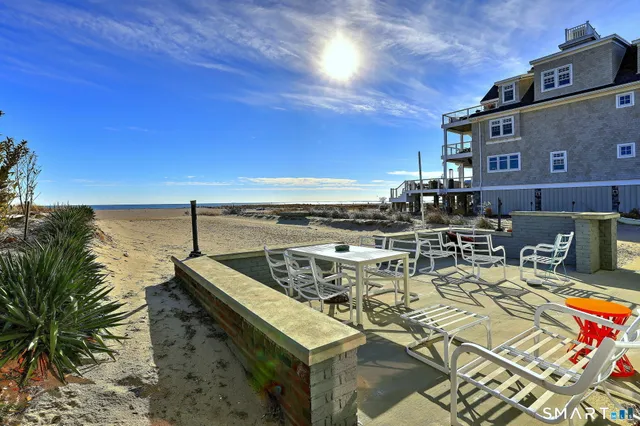 a view of a patio with lawn chairs next to an ocean