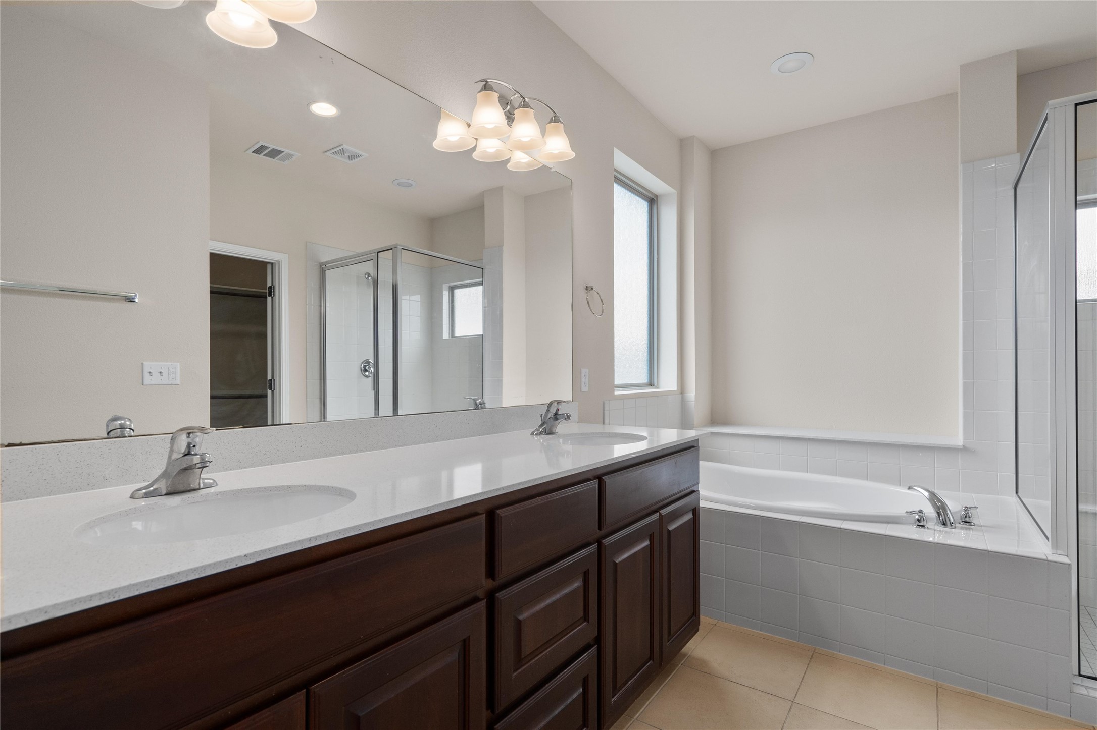 6907 Idea Road Austin, TX 78741 - Photo 14 of 36 a bathroom with a double vanity sink a large mirror and a bathtub