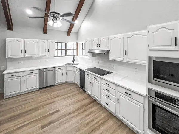 a large white kitchen with cabinets and stainless steel appliances