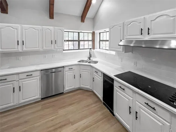 a kitchen with white cabinets appliances a sink and dishwasher