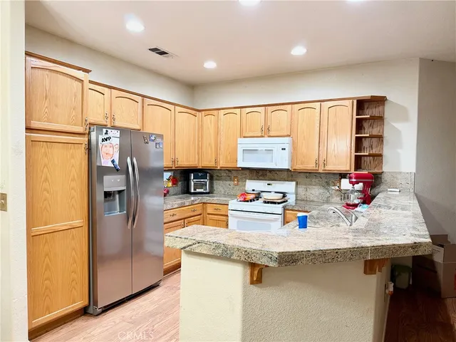 a kitchen with granite countertop a refrigerator stove microwave and sink