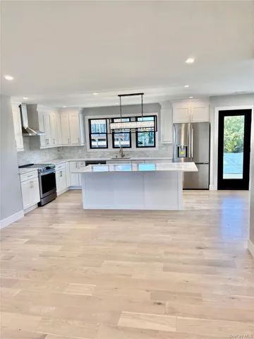 a living room with stainless steel appliances kitchen island a cabinets wooden floor and a fireplace