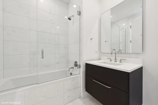 a bathroom with a bath tub sink mirror and shower
