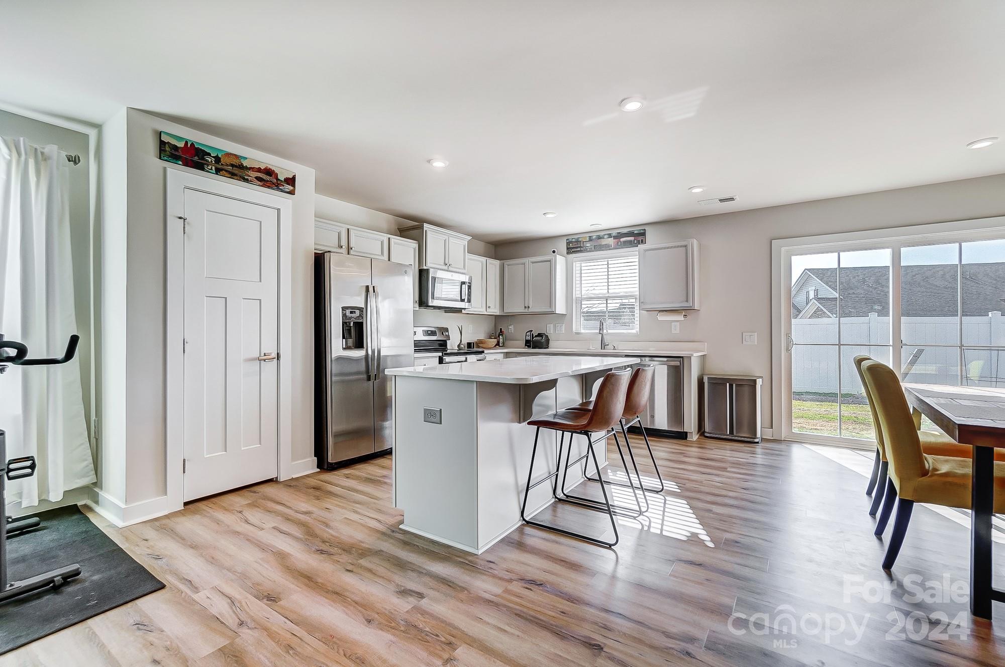 4136 Mackinnon Drive Charlotte, NC 28214 - Photo 9 of 48 a kitchen with stainless steel appliances a dining table chairs a refrigerator and cabinets