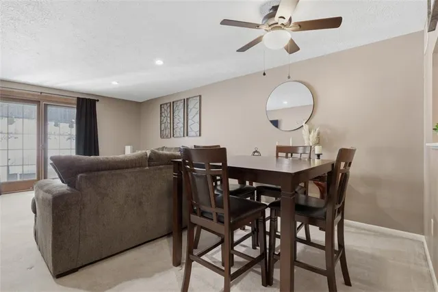 a living room with furniture a chandelier fan and a large window