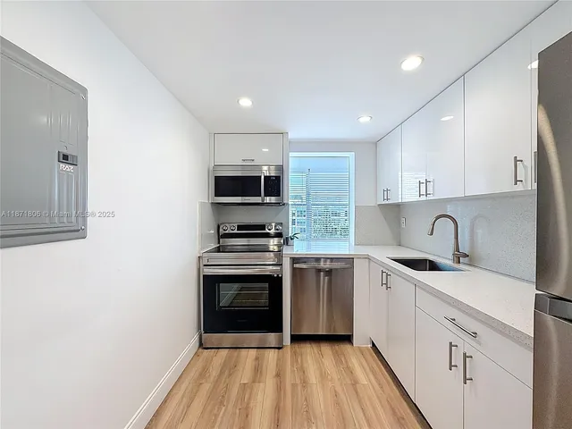 a kitchen with a sink stainless steel appliances and white cabinets