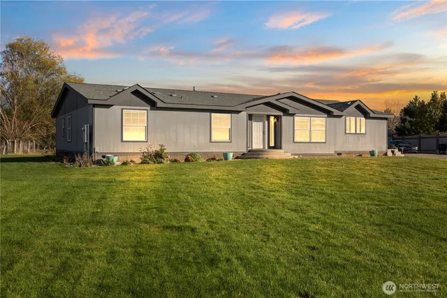 a front view of house with yard and trees in the background