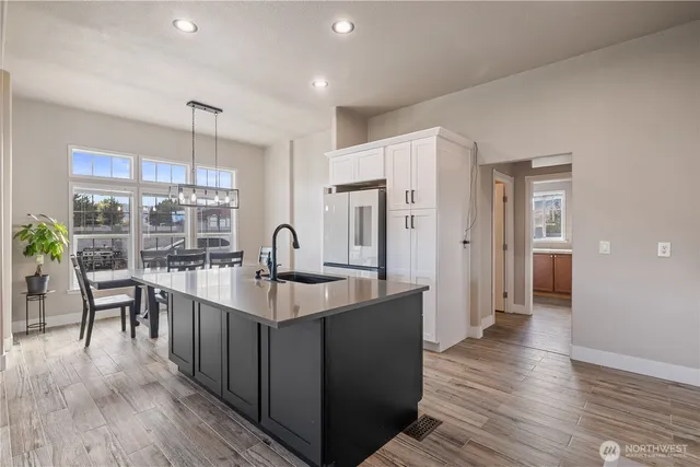 a large white kitchen with wooden floor and a large window