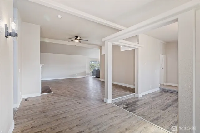 an empty room with wooden floor and a ceiling fan