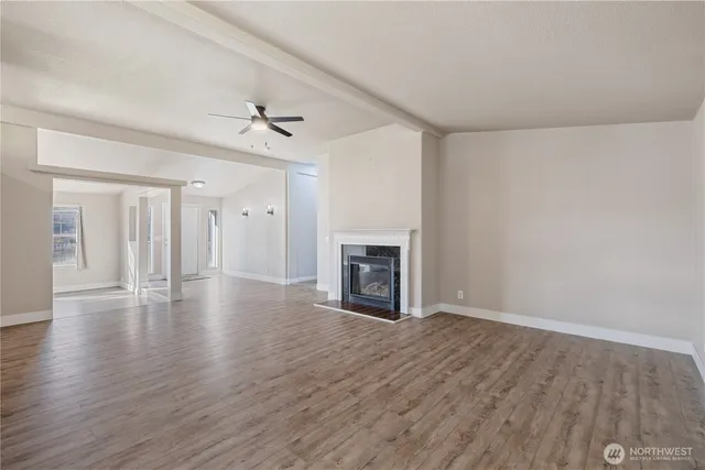 an empty room with wooden floor fireplace and windows