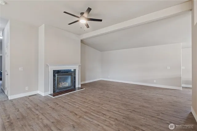 a view of empty room with wooden floor and fireplace